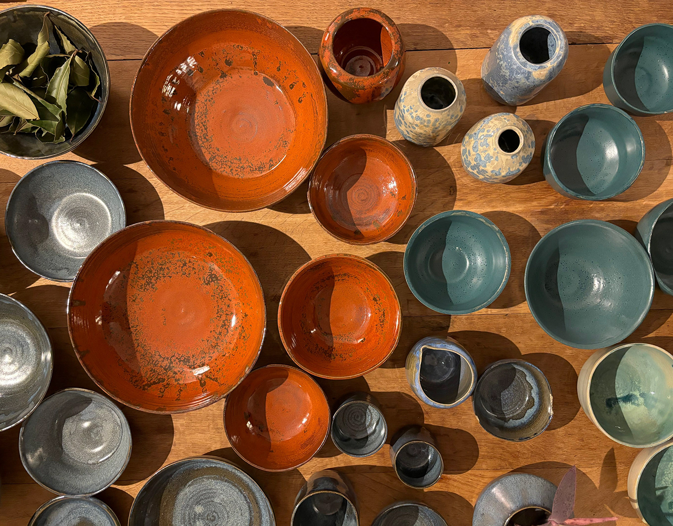 A table filled with handmade bowls and vessels